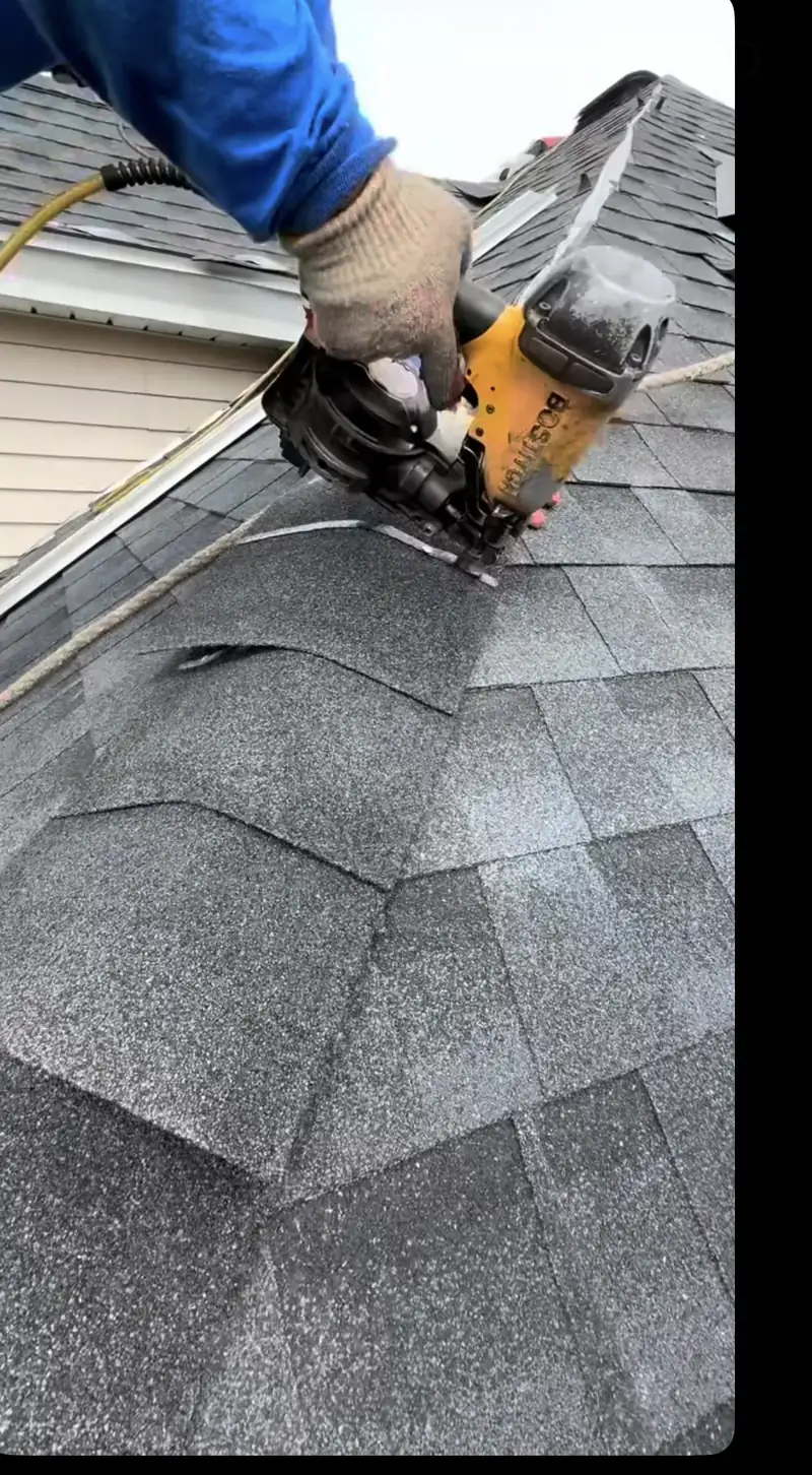 Close-up of a roofing nailer fastening ridge cap shingles